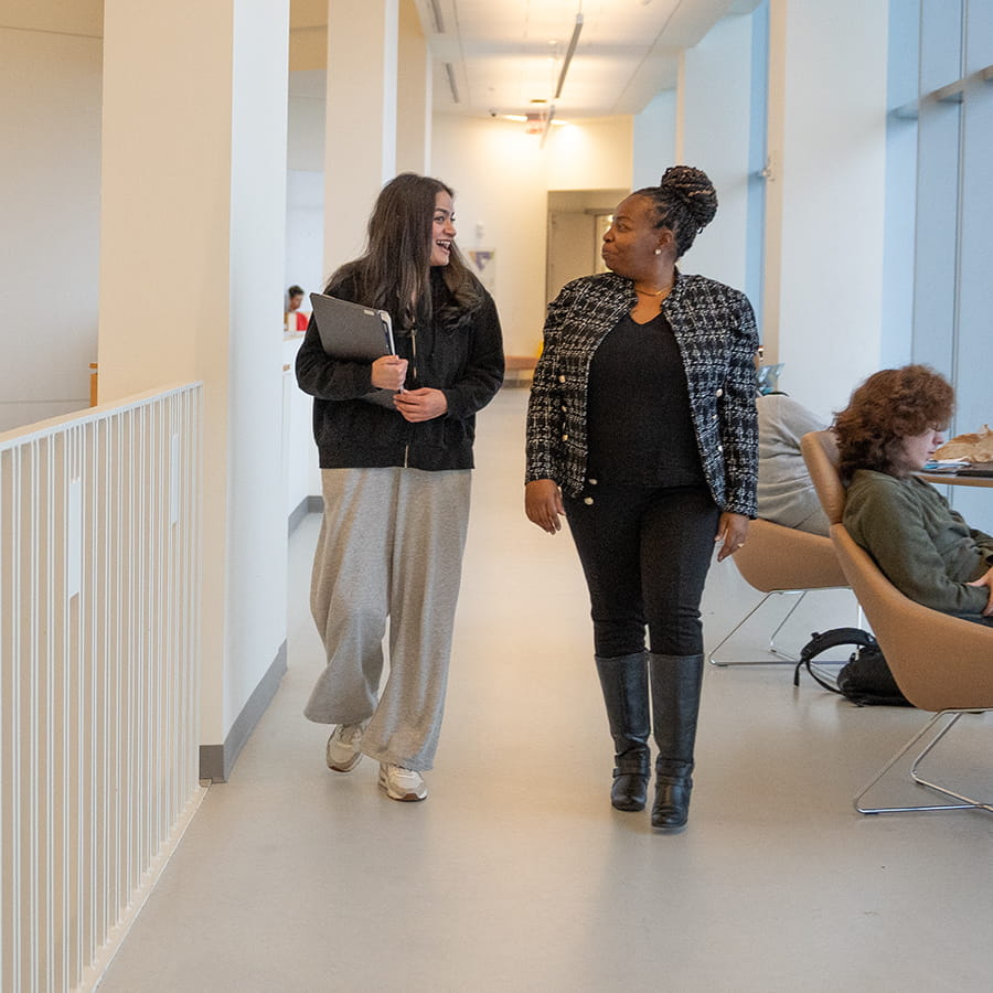 Staff walks with student in University Hall balcony.